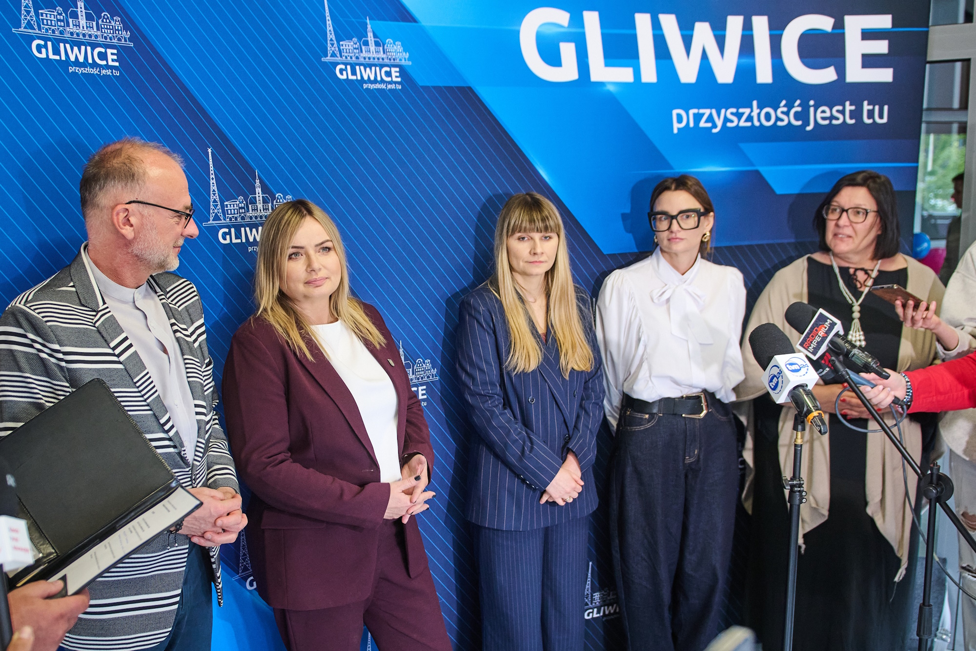 osoby na ściance prasowej udzielają wywiadów podczas konferencji