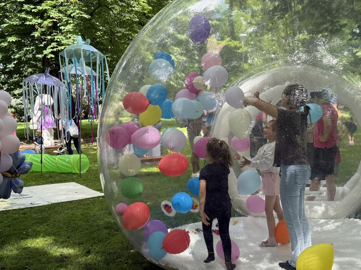 dzieci w wielkiem bańce wypełnionej balonami