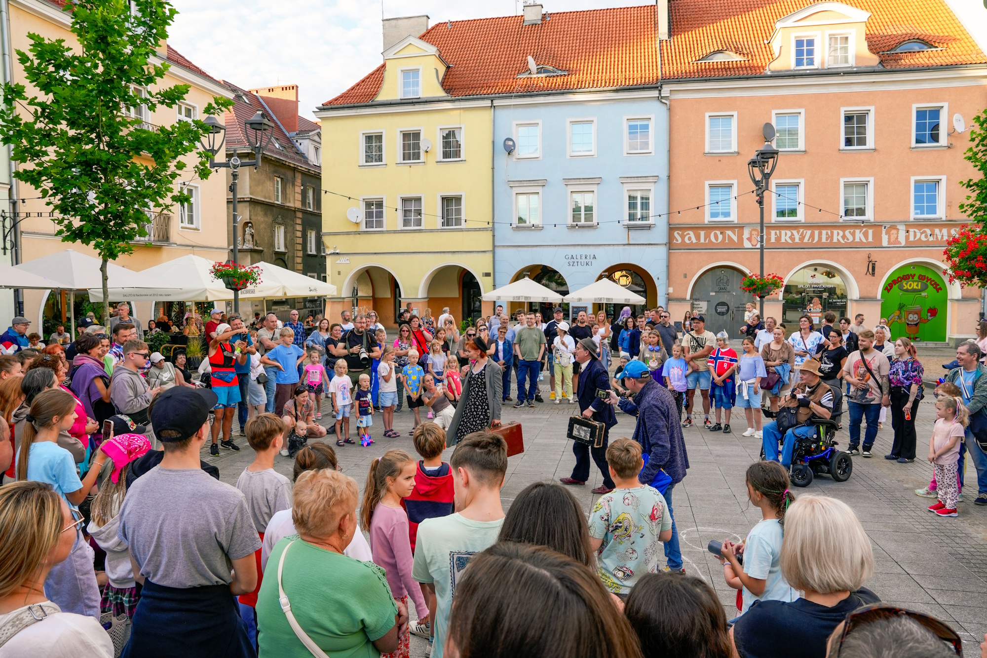 Aktorzy występują na ulicy, wokół zgromadzeni ludzie