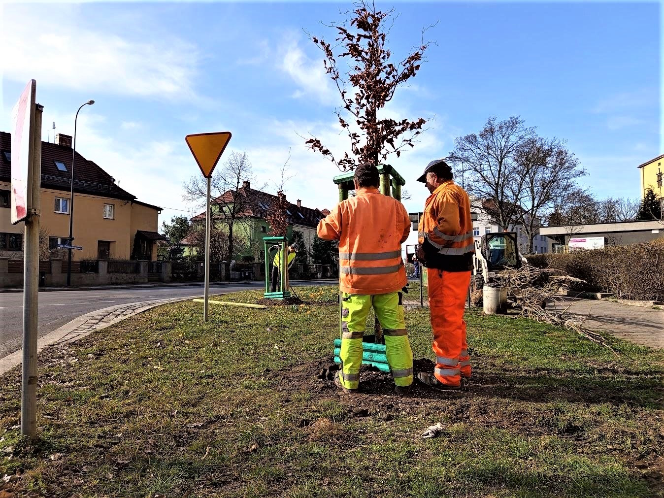 dwóch panów ubranych na pomarańczowo trzyma drzewo