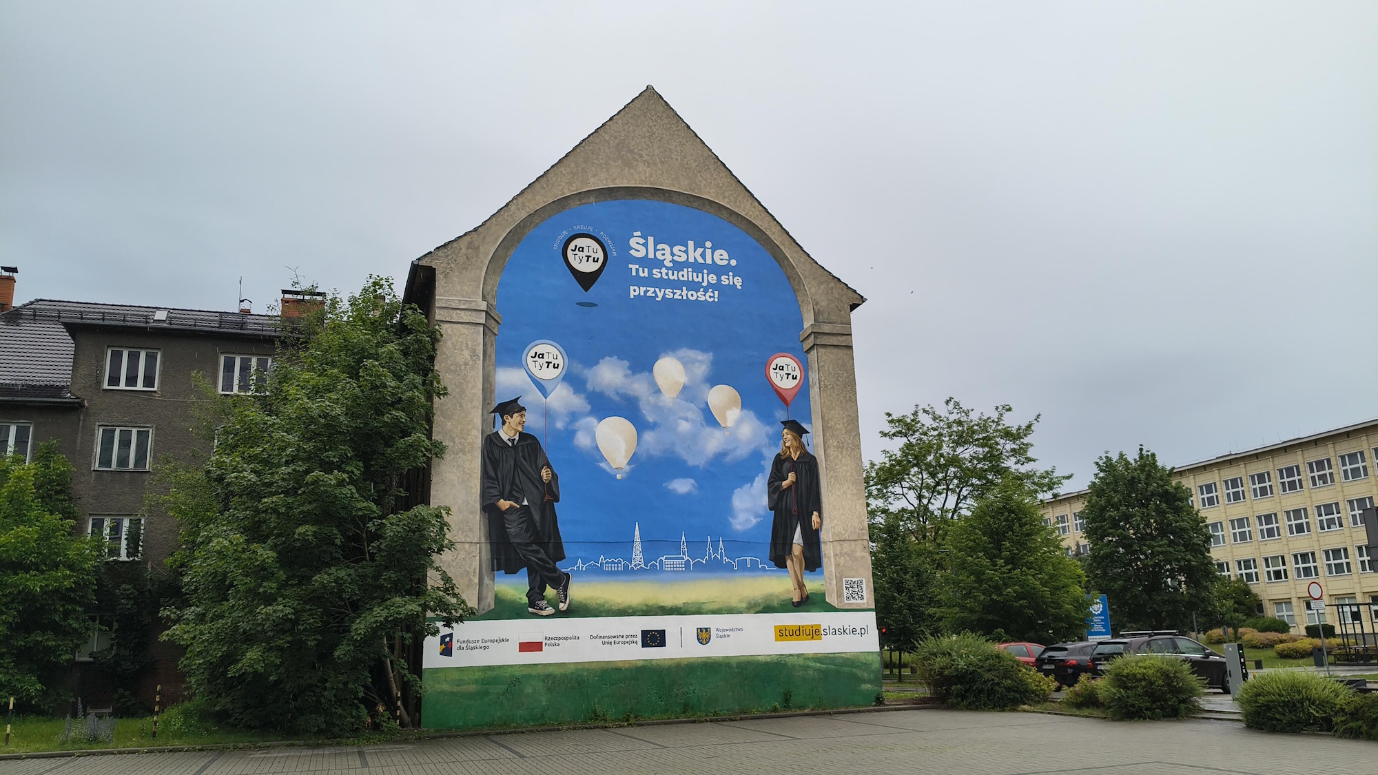 mural na budynku. Pokazuje dwoje ludzi w akademickich strojach