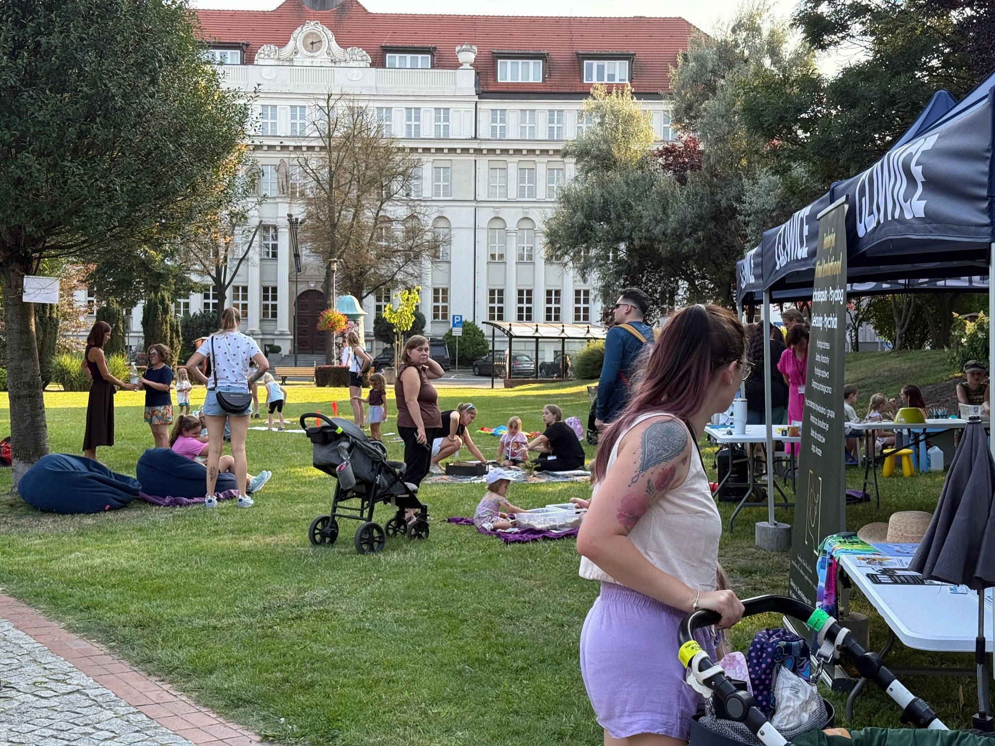 ludzie z dziećmi na trawie przy namiotach 