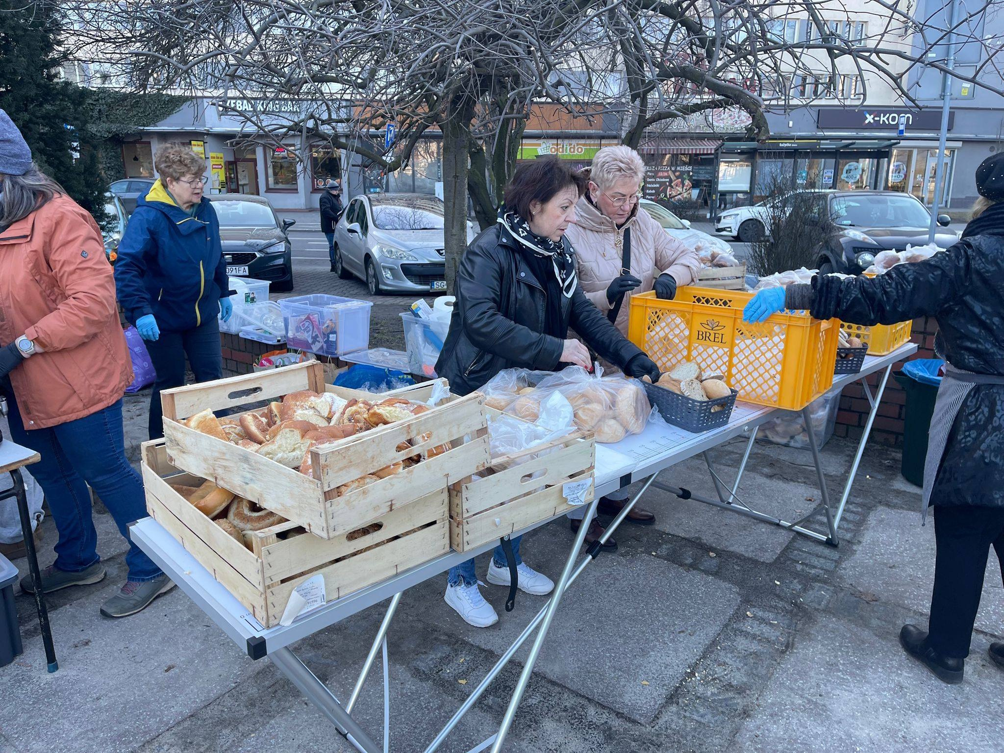 ludzie przy stołach zastawionych pieczywem