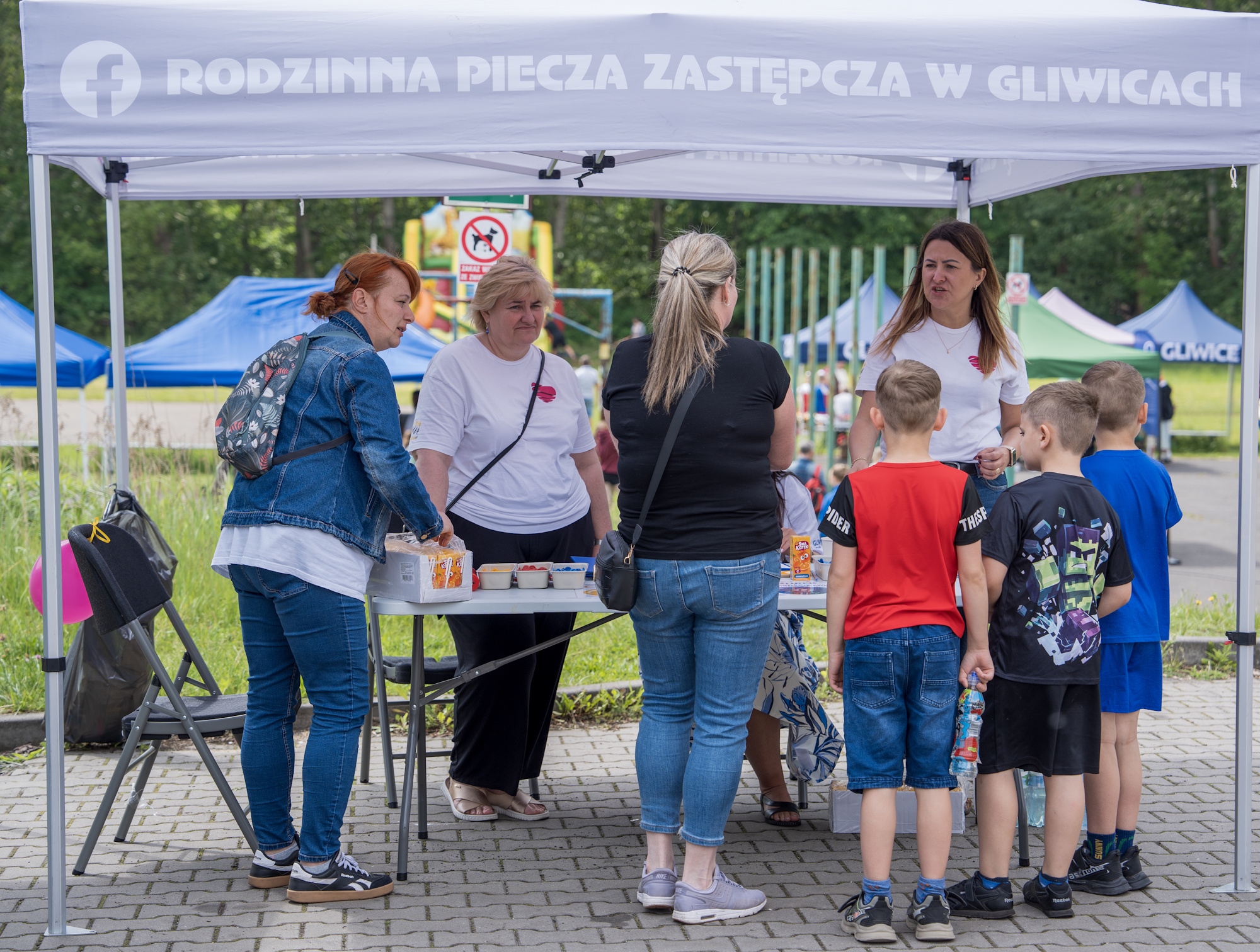 dzieci i dorośli przy stoisku pieczy zastępczej podczas festynnu rodzinnego