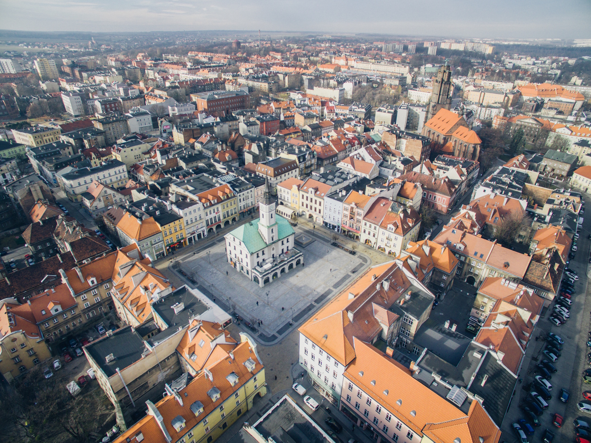 widok na gliwicki Rynek, jego Ratusz i kamienice, z szarym niebem w tle